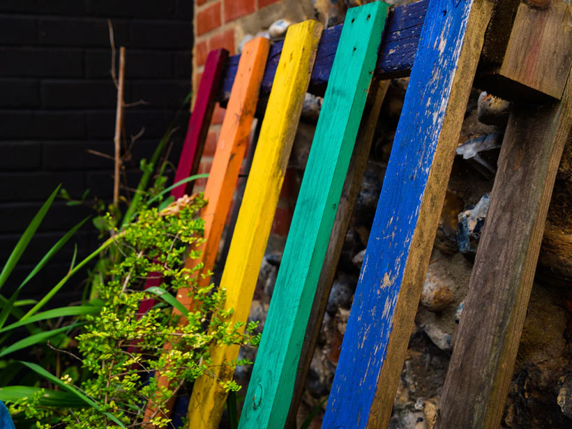 An upcycled pallet painted in rainbow colors livens up a garden setting