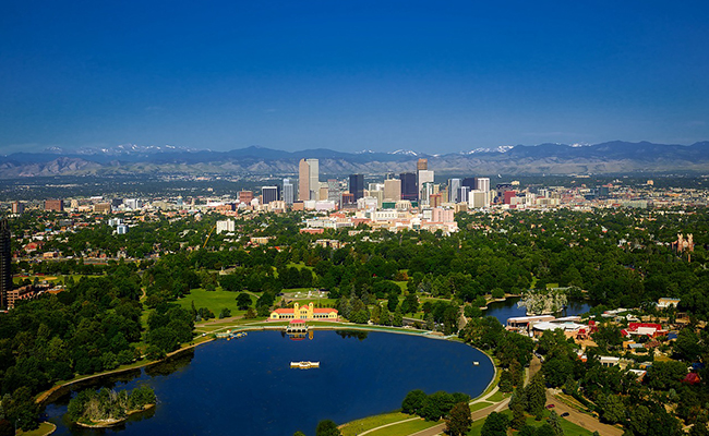 The Denver, Colorado skyline with the Rocky Mountains in the background and a beautiful pond in the foreground. 