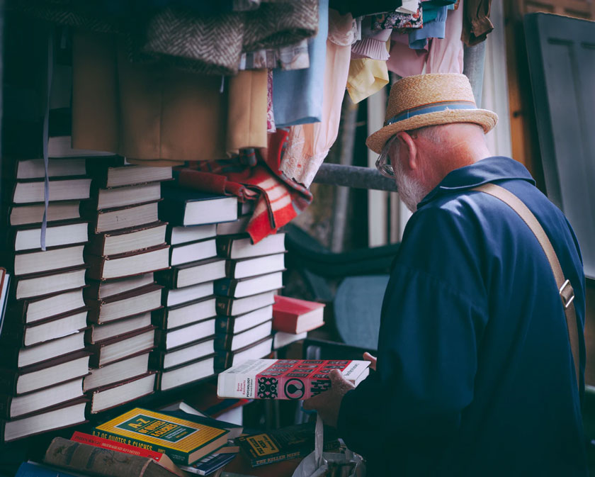 Man at a garage sale looking through stacks of books