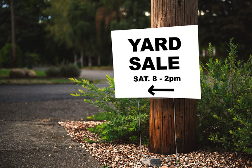 A yard sale sign on the roadside.
