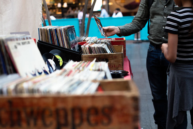 A man and his daughter look at a table stack with used vinyl records for sale