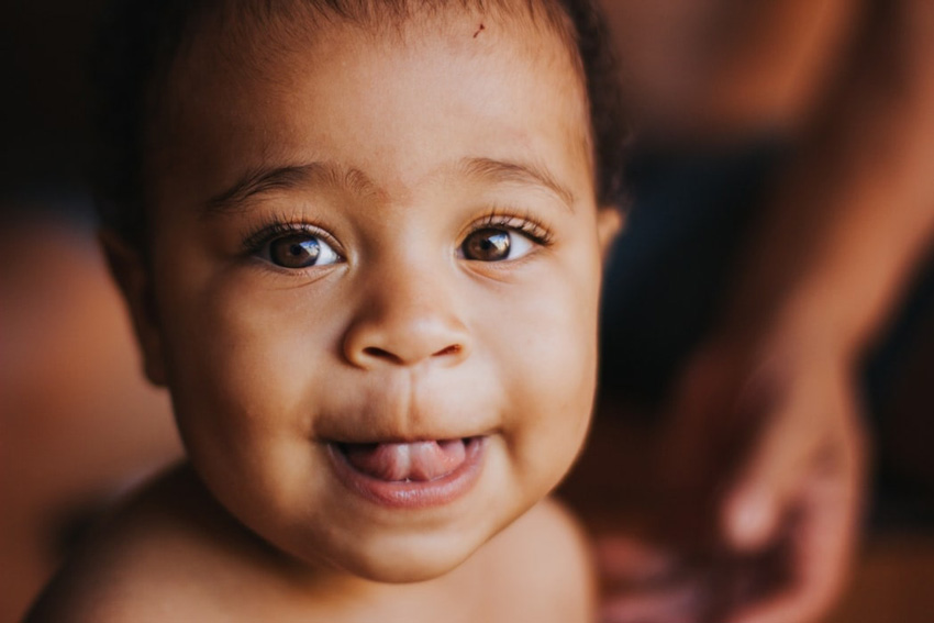 A close up of a brown-eyed baby smiling at the camera