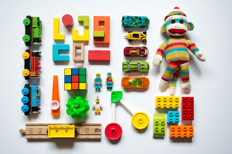 A selection of colorful kids’ toys on a white surface as an example of the best yard sale items to sell